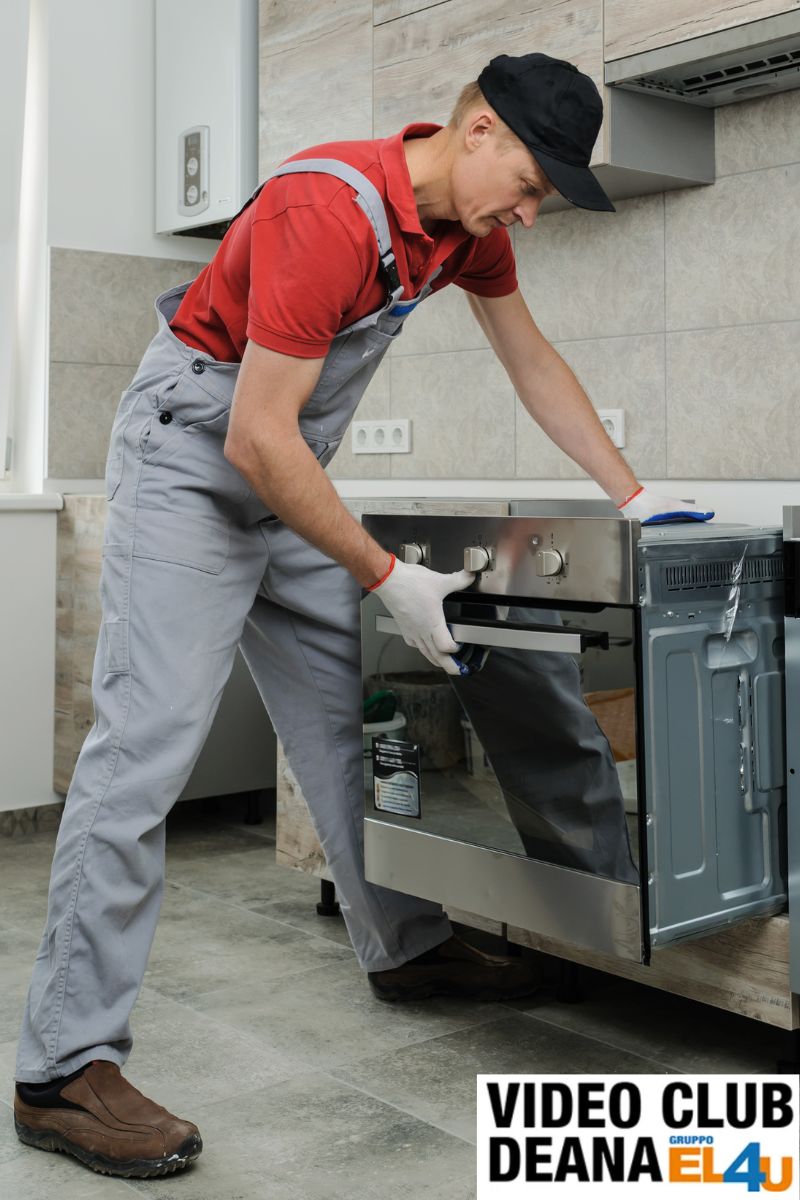 Tecnico specializzato installa un forno da incasso in una cucina moderna, completando il collegamento elettrico. Servizio di installazione elettrodomestici a domicilio in Friuli Venezia Giulia.
